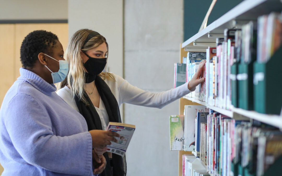 Young women browsing books at library