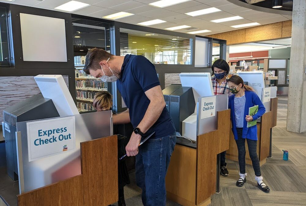 Family using self-check machines at Sequoya Library