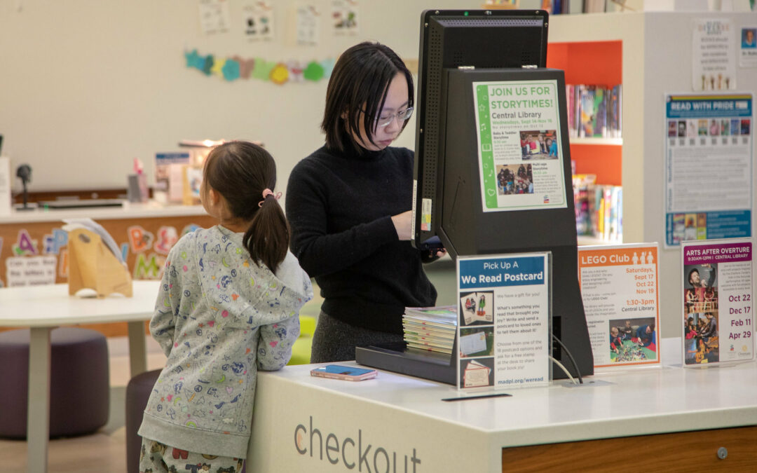 Mom and daughter checking books out at Madison Central Library using self-check machine