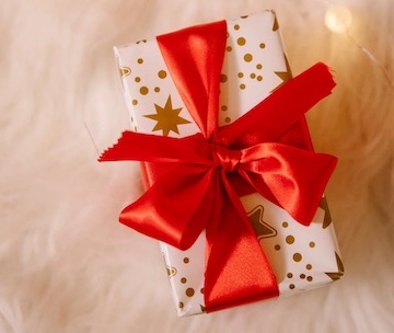 Small gift wrapped in holiday paper with red bow