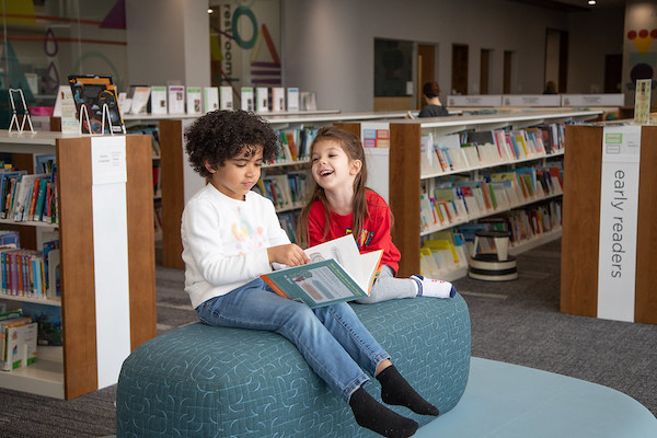 Two preschool-age girls reading in library