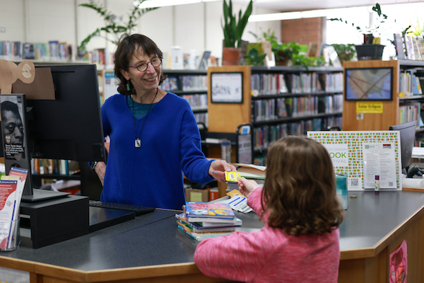 Monroe Street Library staff member handing library card to young patron
