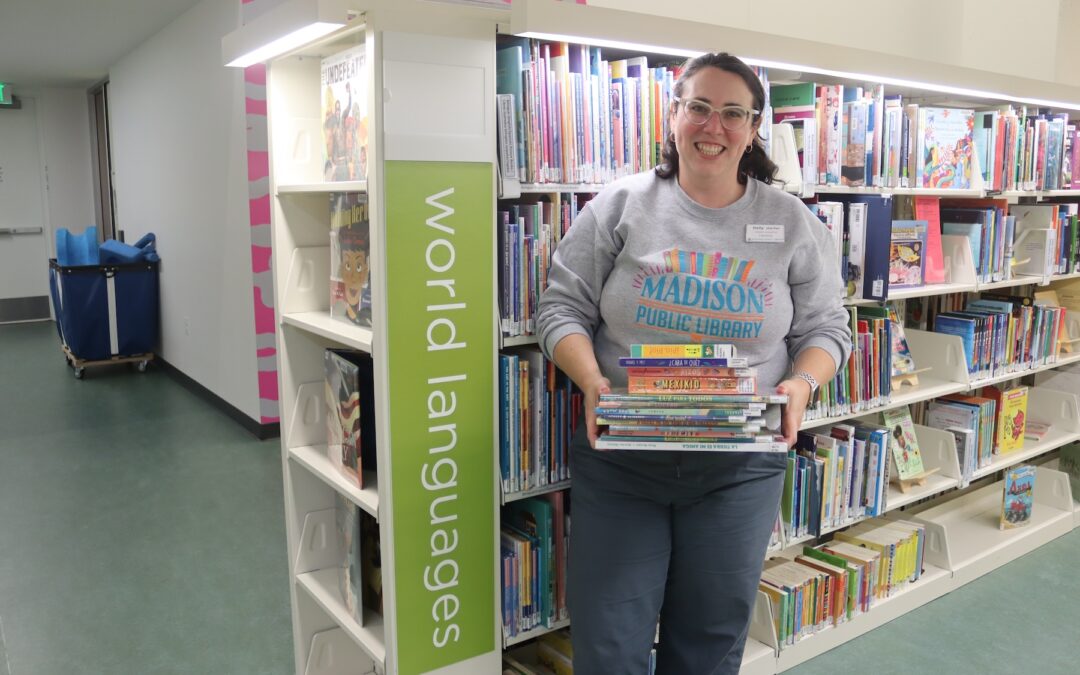 Children's Librarian Holly Storck-Post with stack of recently relabeled World Language Collection materials